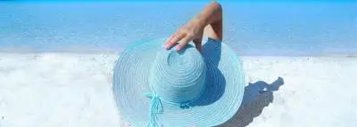 Crème solaire : que choisir pour l'été ? bord mer sable femme chapeau